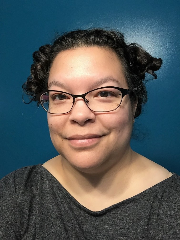 Lisa M. Bradley smiling while wearing glasses. Lisa's hair is up and she is wearing a dark blouse.
